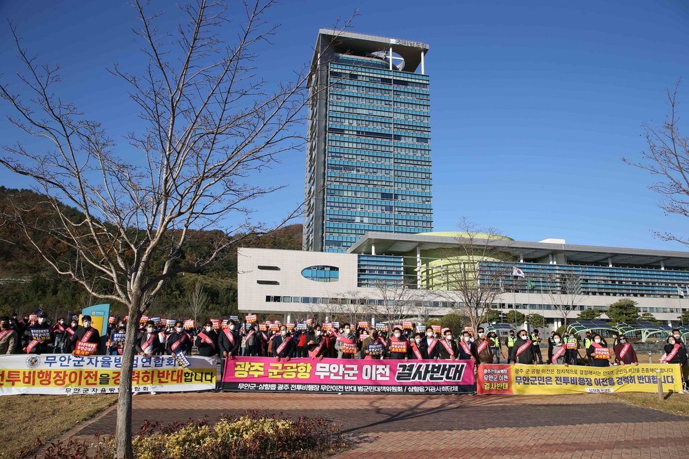 전투비행장이전을 강력히 반대합니다, 광주군공항 무안군 이전 결사반대, 무안군민은 전투비행장 이전을 강력히 반대합니다 등의 현수막을 든 사람들이 전남도청 앞에서 기념촬영을 하고있는 모습