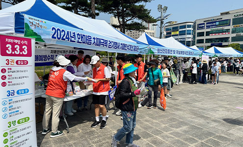 2024년 한마음 치매극복 걷기행사 치매인식 홍보관이 나란히 천막을 치고 있으며 지나가는 시민들이 홍보지를 받아가는 모습