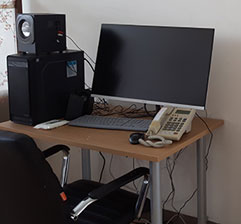 책상에 컴퓨터와 스피커 그리고 전화기가 놓여져있다.