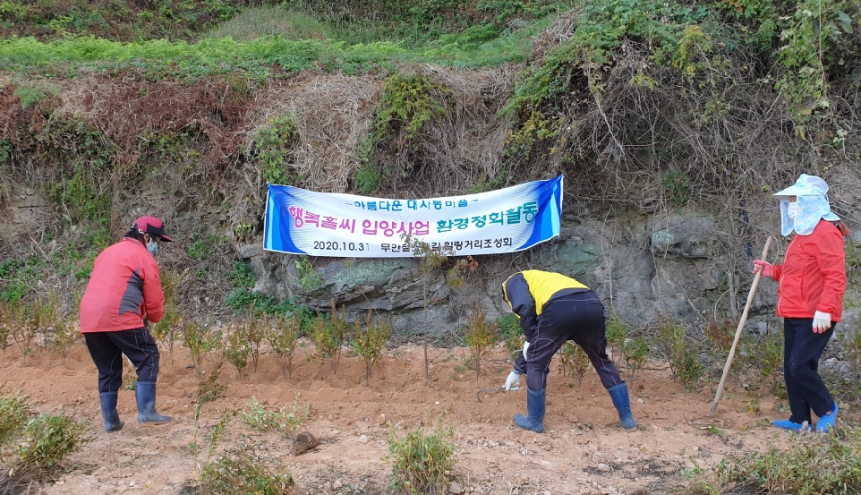 무안읍 행복홀씨 입양사업 환경정화활동을 위하여 세명의 사람들이 화단에서 작업복을 입고 작업하고 있다. 